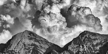 Ein Gleitschirmflieger vorm Sonntagshorn mit Wolken-Explosion, in schwarz-weiß.