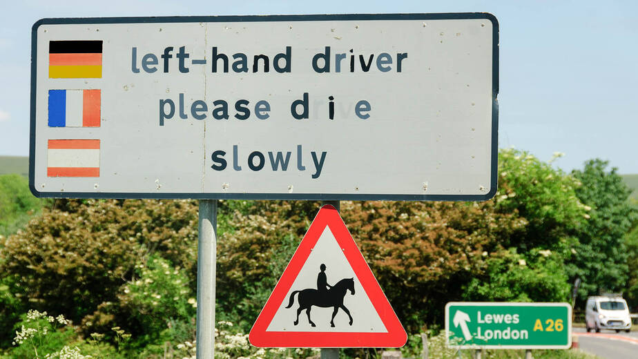 Ein Straßenschild als "Willkommensgruß" an die Europäer. Left-hand driver please drive bzw. "die" slowly.